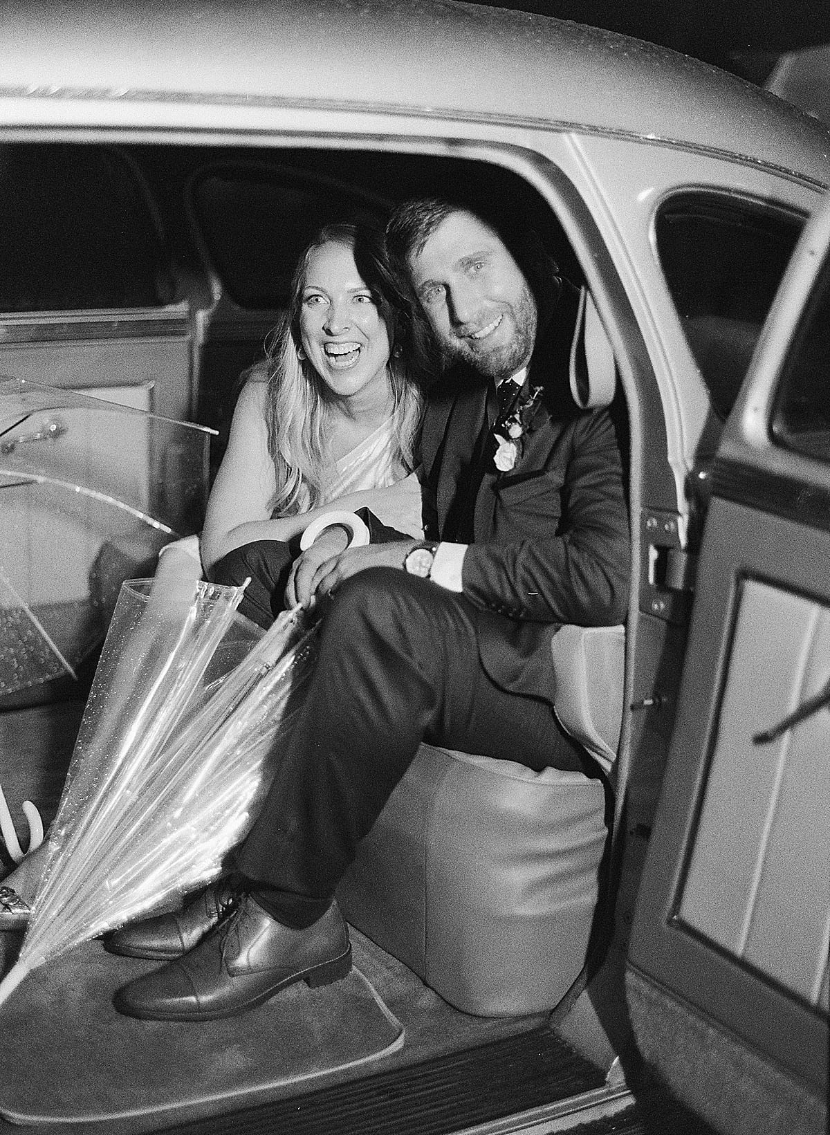 Black and White of Bride and Groom in Getaway Car Smiling Photo