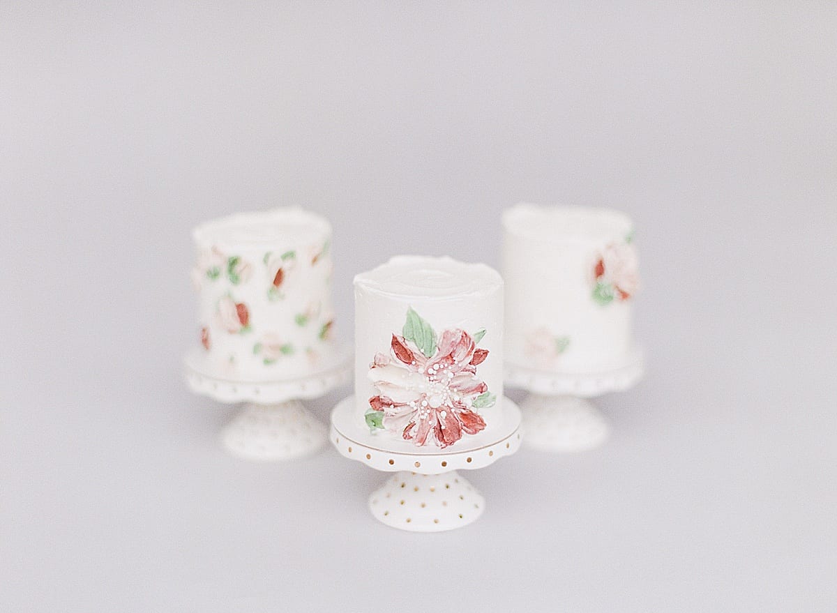 Three Small Cakes with Pink and Red Flowers on Small Pedestals Photo