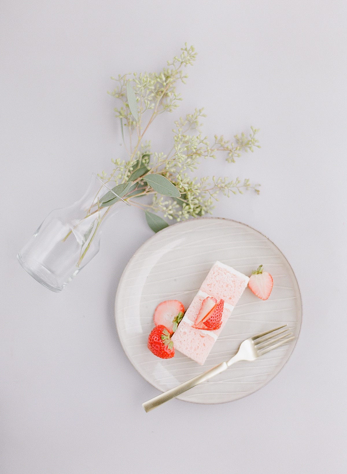 Strawberry Cake on Plate with Vase of Seeded Eucalyptus Photo