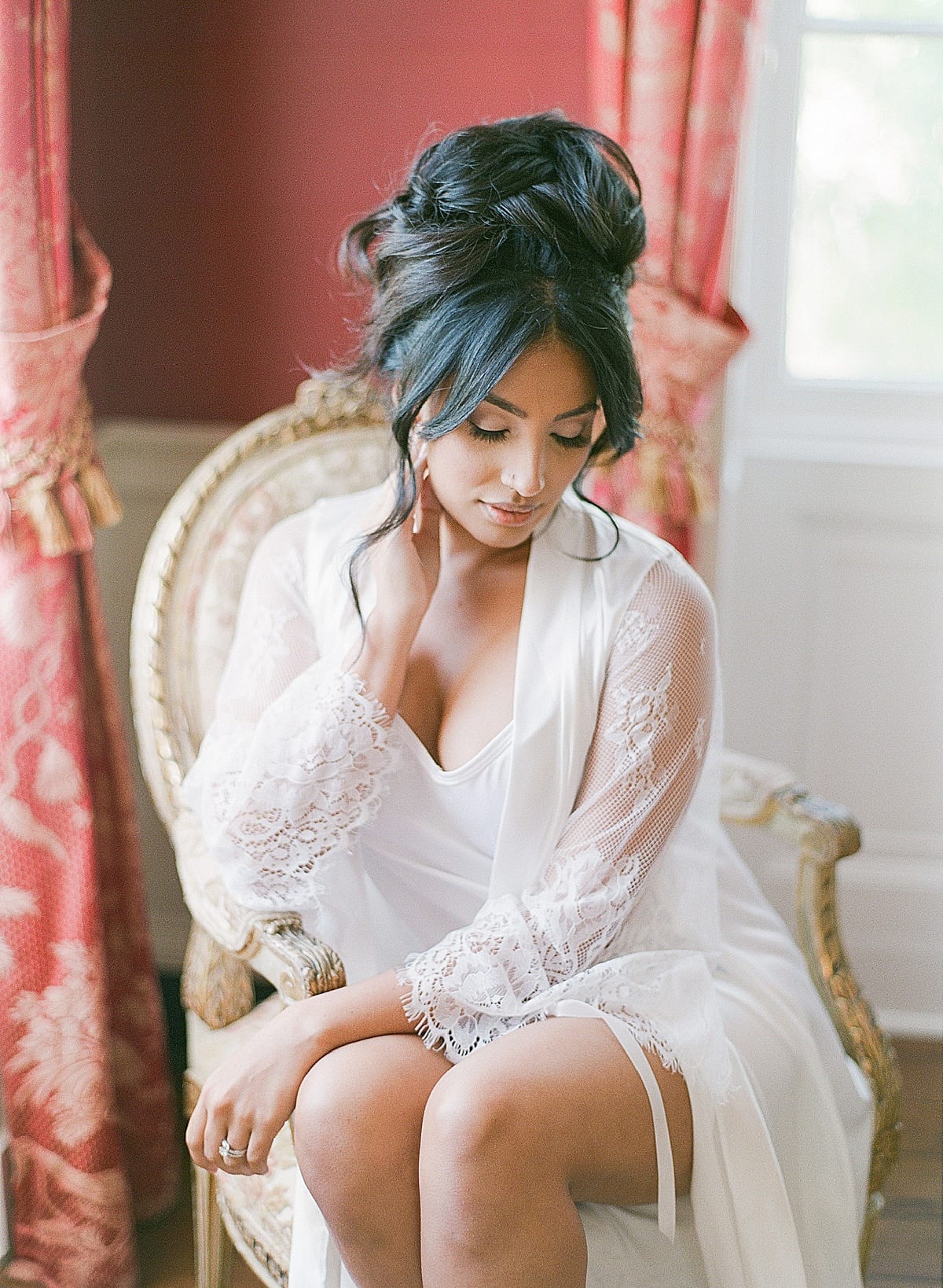 Bride in Lace Robe Sitting in Chair Looking Down Photo