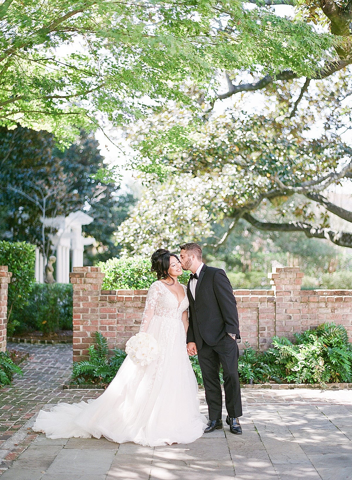 Groom Kissing Bride on the Cheek in Garden at William Aiken House Photo