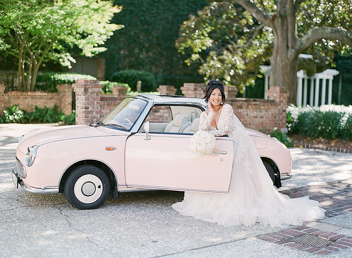 Bride Leaning on Door of Vintage Pink Car Photo