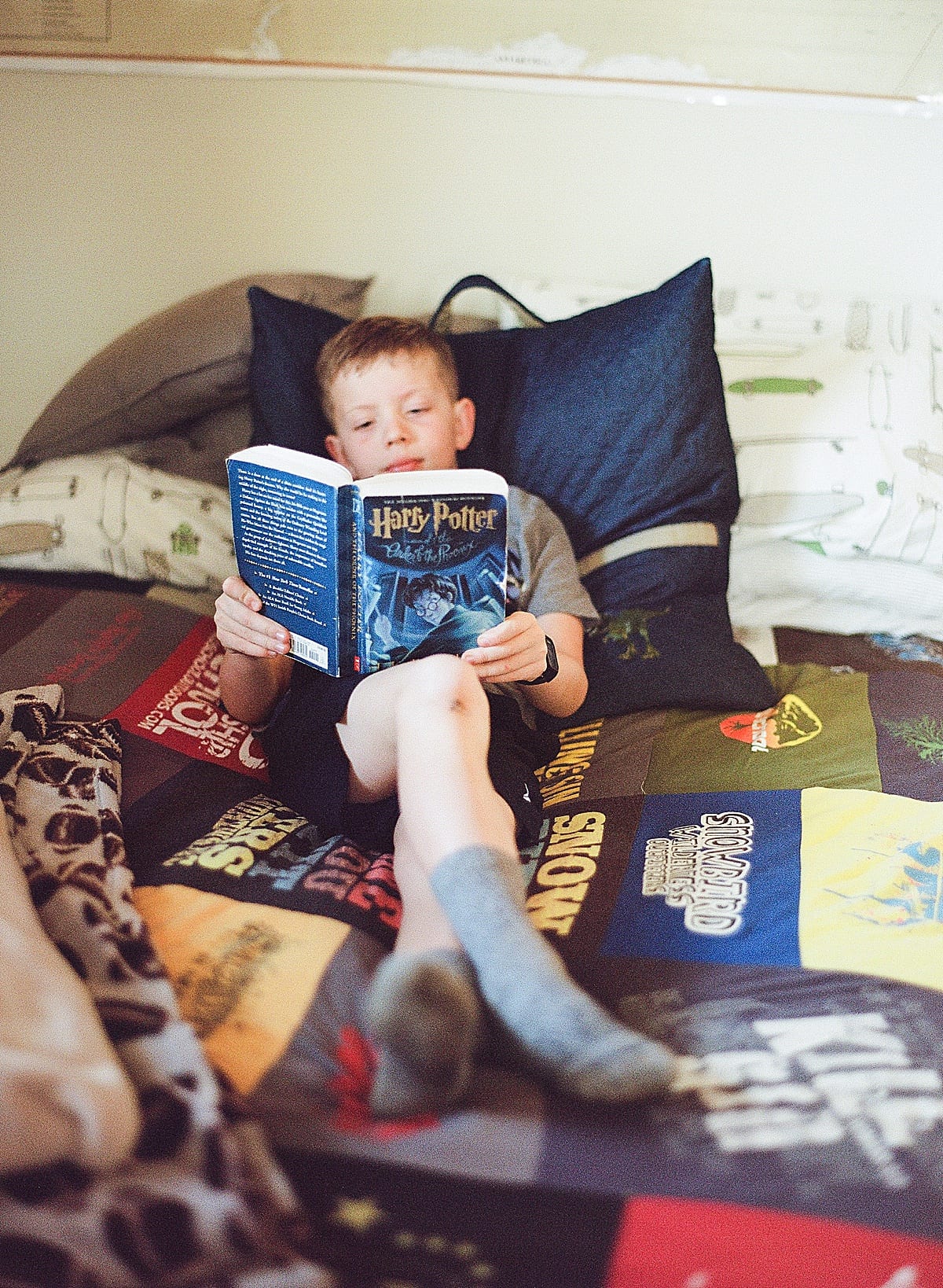 Boy on bed reading Harry Potter Photo