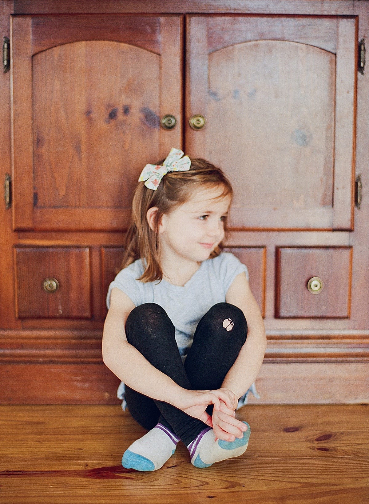 Little girl looking off with legs crossed sitting on the ground photo