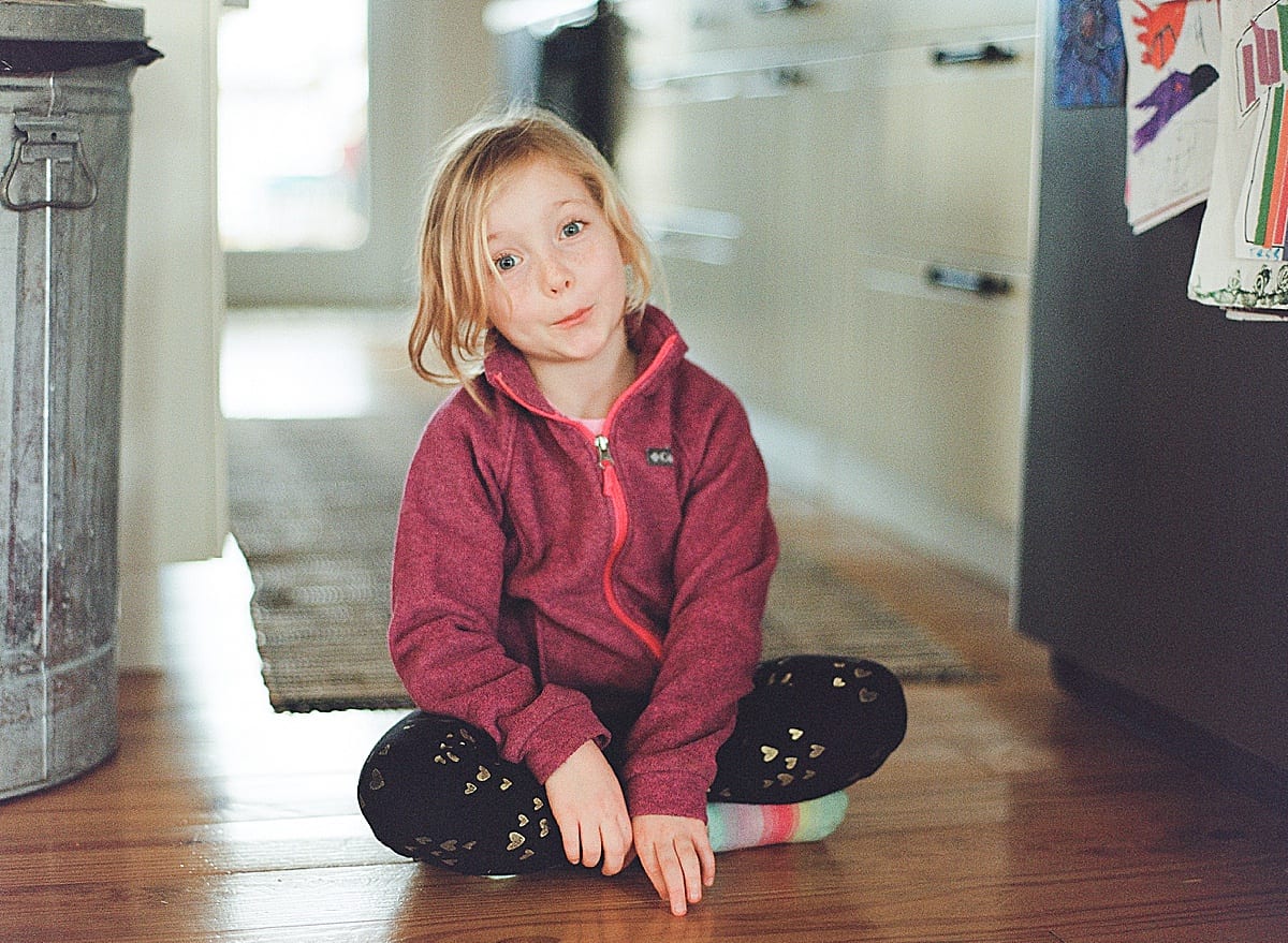 little girl sitting in kitchen floor silly face photo 