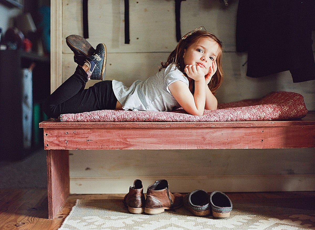 Little girl smiling laying on bench photo