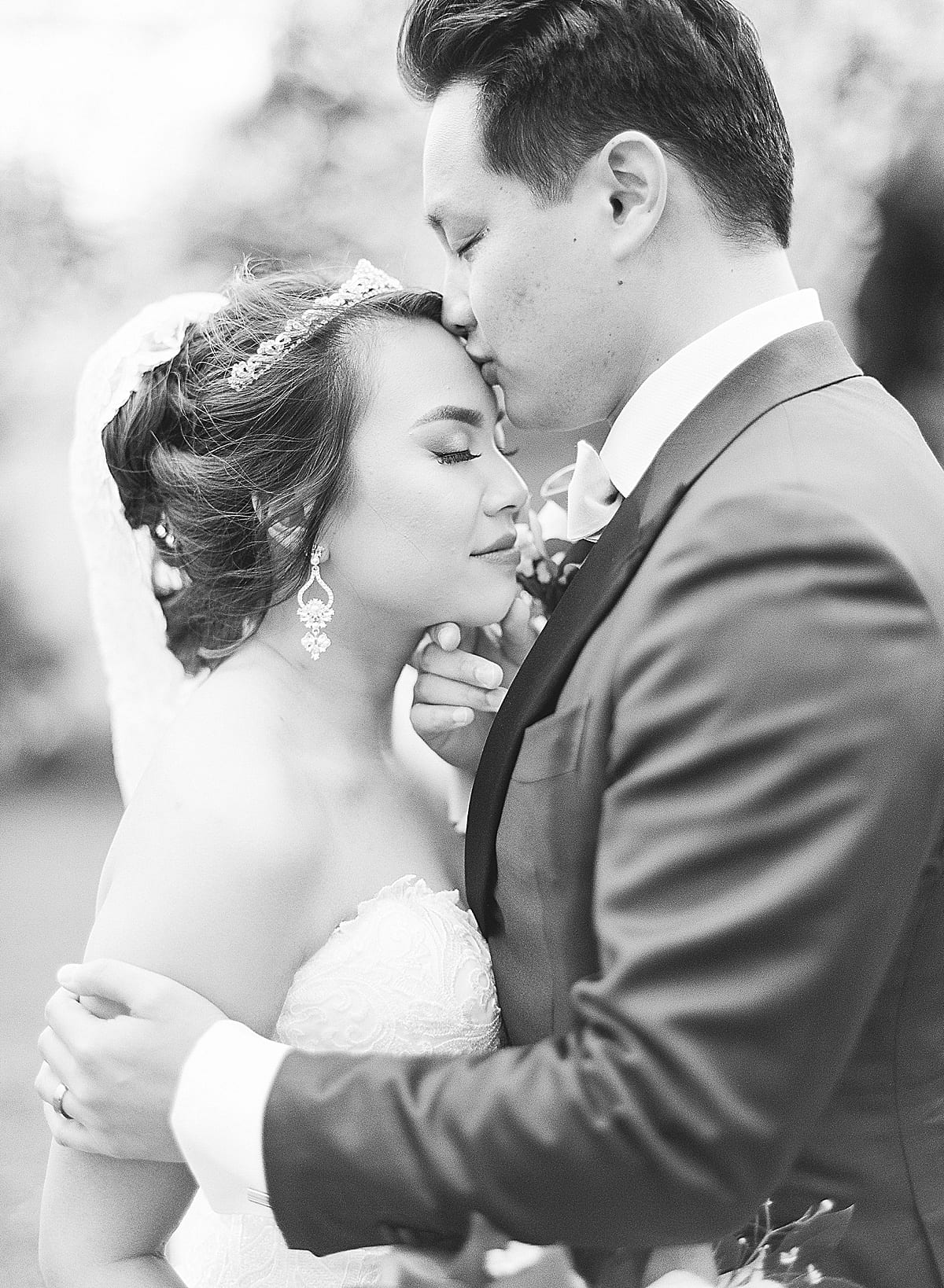 Black and White of Groom Kissing Bride on Head Photo