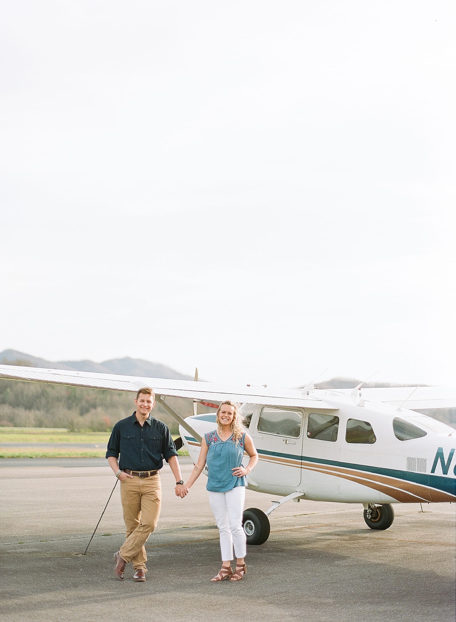 couple holding hands in front of plane at local airport photo