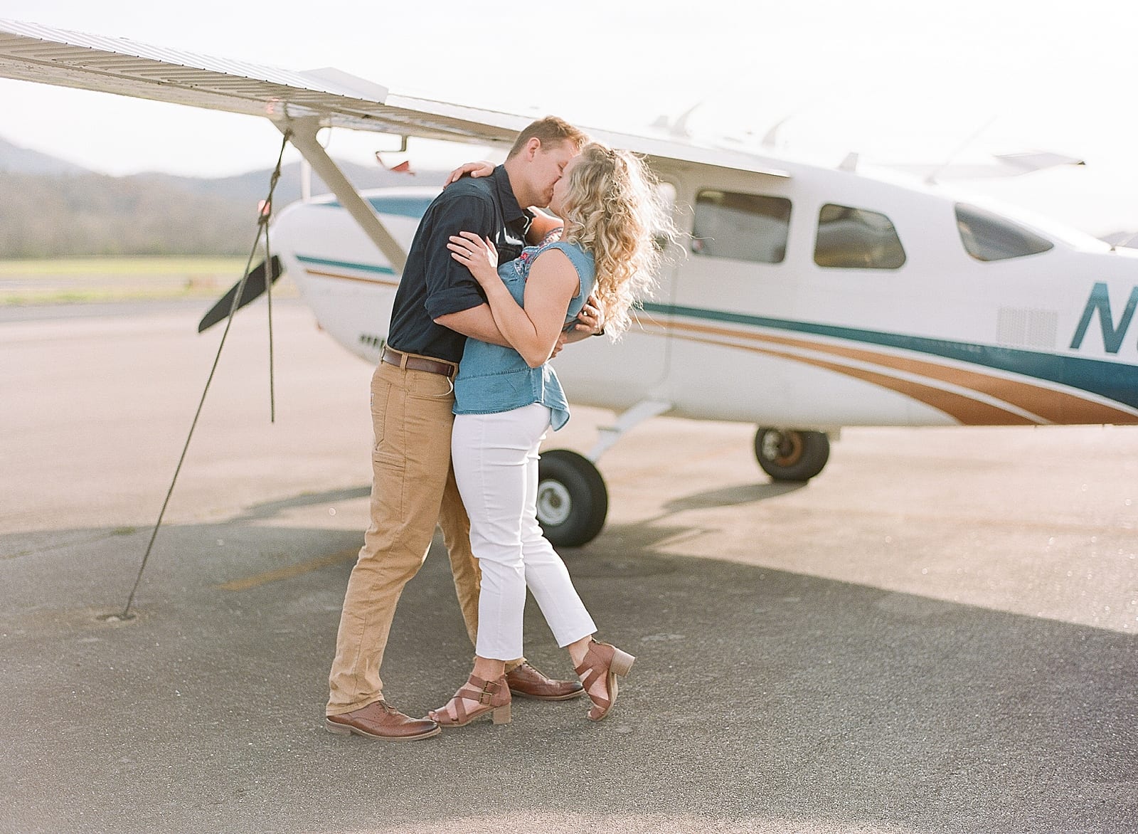 Couple kissing in front of plane photo