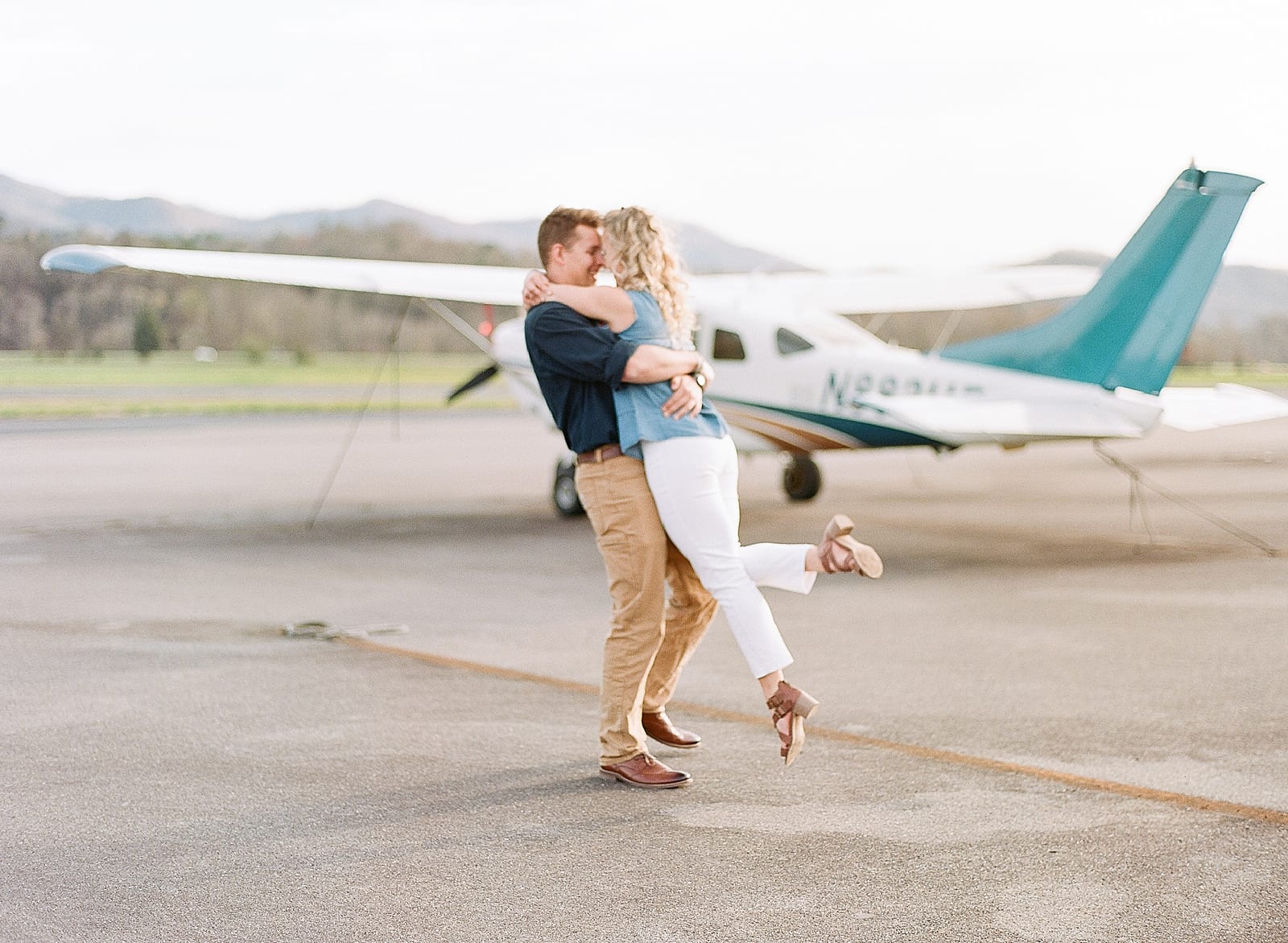couple spinning in front of airplane at airport photo