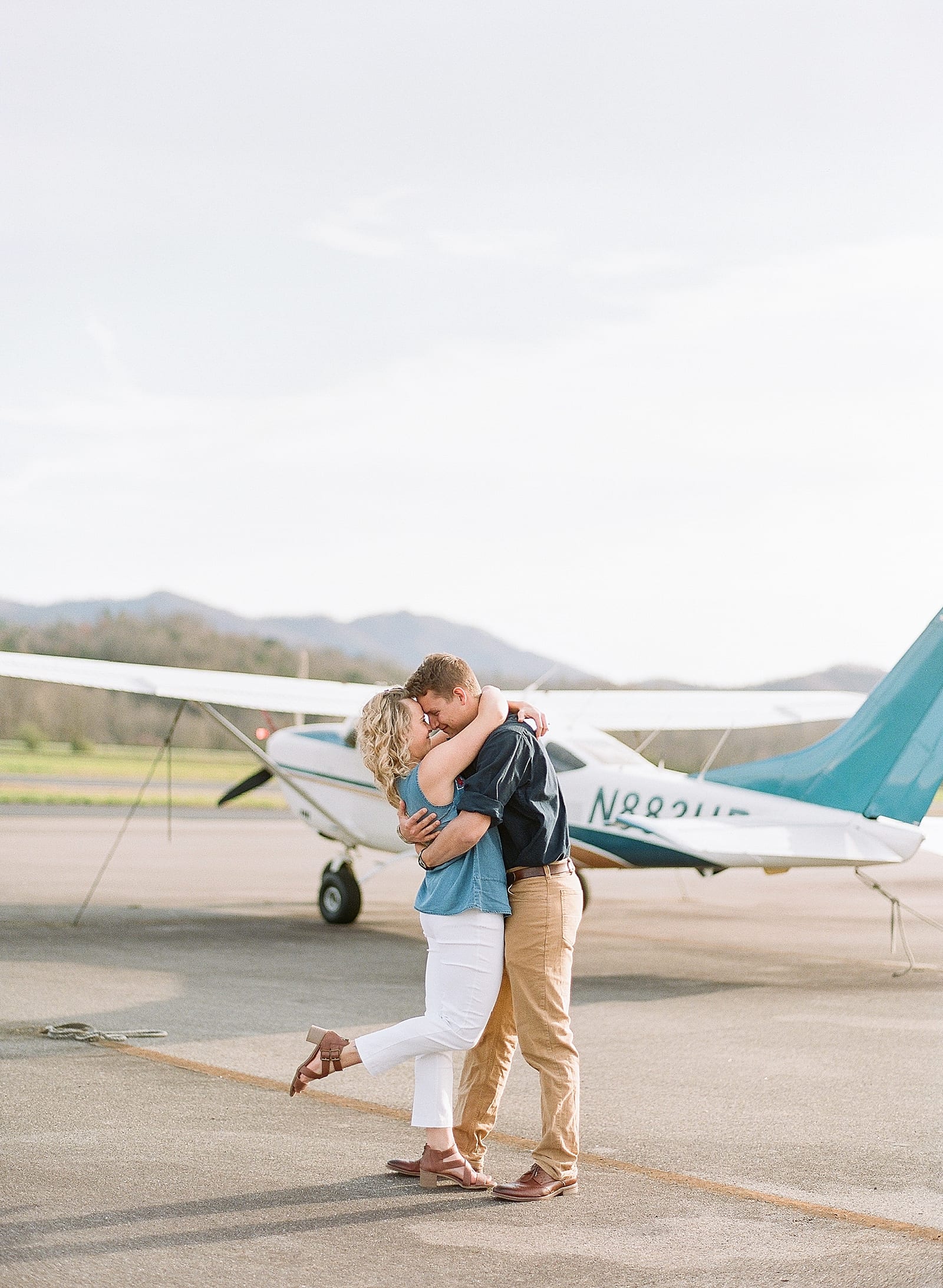 couple kissing in front of plane at airport photo