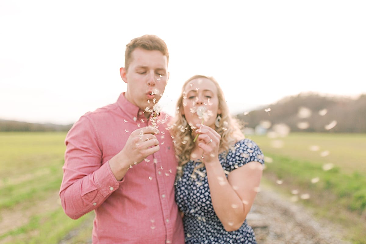 Couple blowing dandelions in field photo