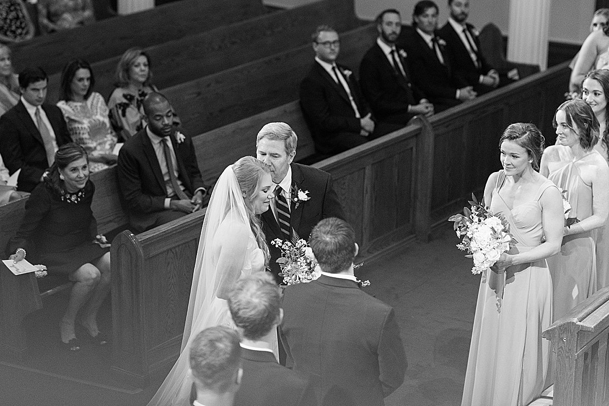 Black and White of Dad Kissing Bride at End of Aisle Photo