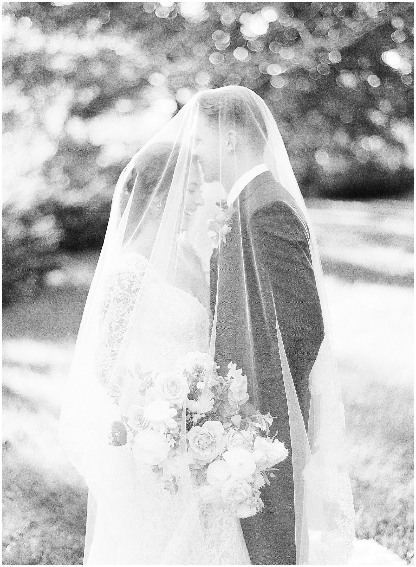 Black and White of Bride and Groom Laughing Under Veil Photo
