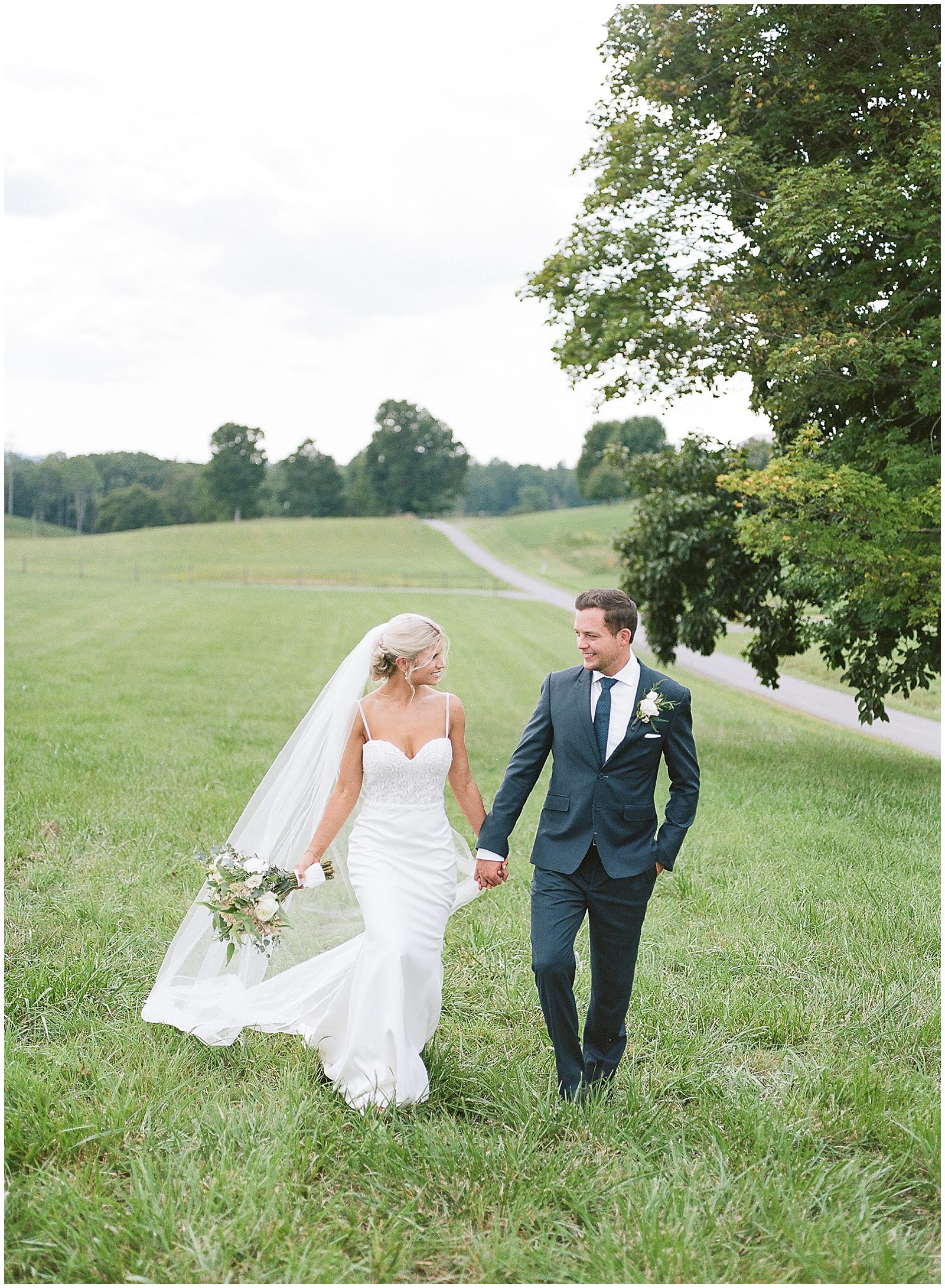 Bride and Groom Walking In Field at Their West Virginia Wedding Photo