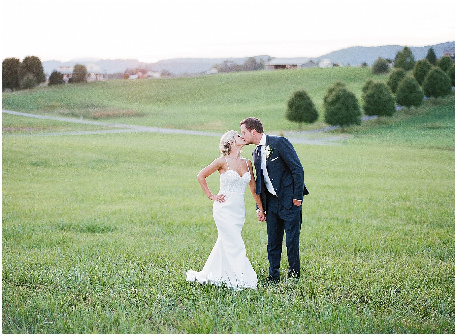 Bride and Groom Kissing In Field Photo