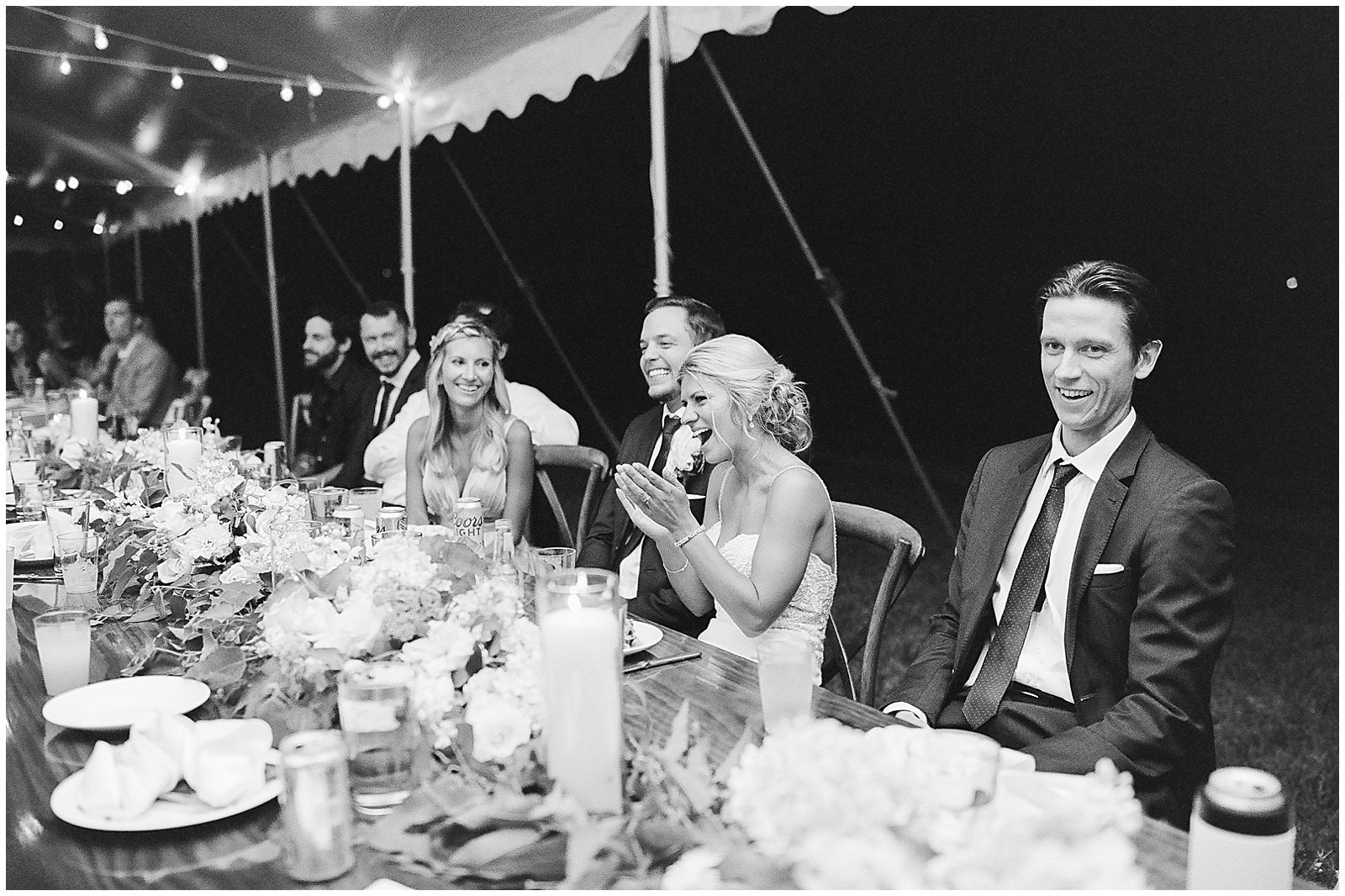Black and White of Bride and Groom Laughing During Toasts at Wedding Reception Photo