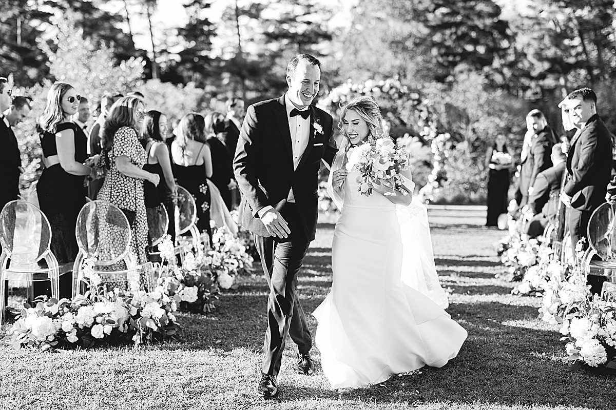 Black and White of Bride and Groom Walking Down Aisle Photo