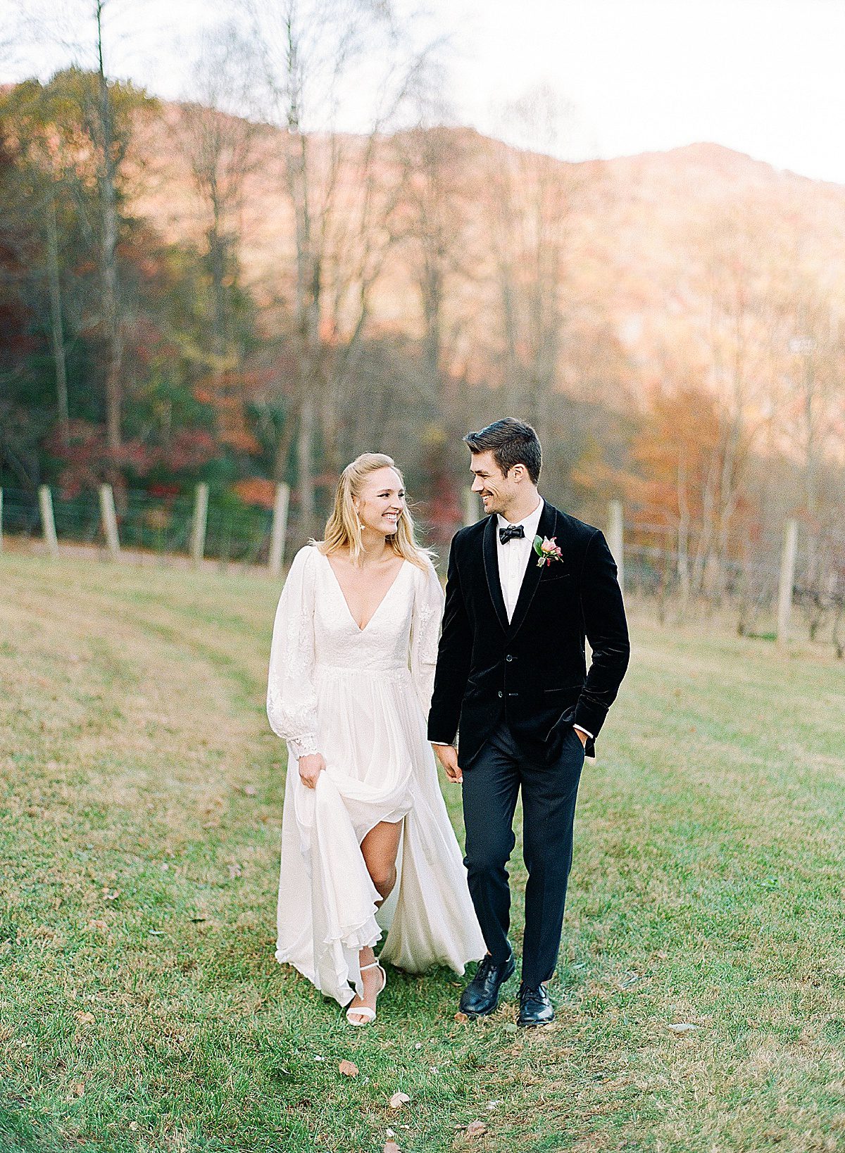 Bride Walking with her groom in Long Sleeve Leanne Marshall Gown Photo