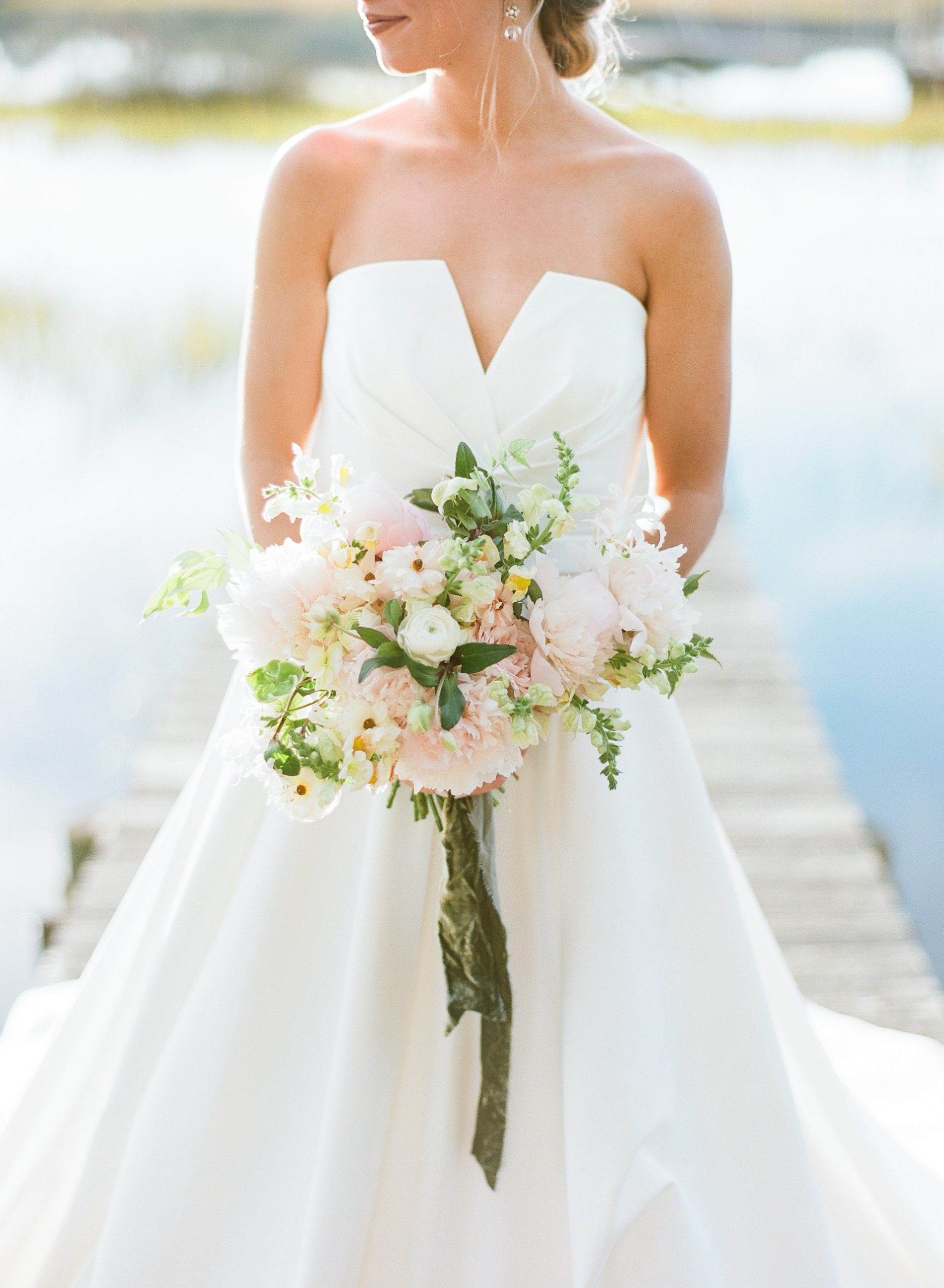 Bride holding blush and white bridal bouquet with green ribbon photo