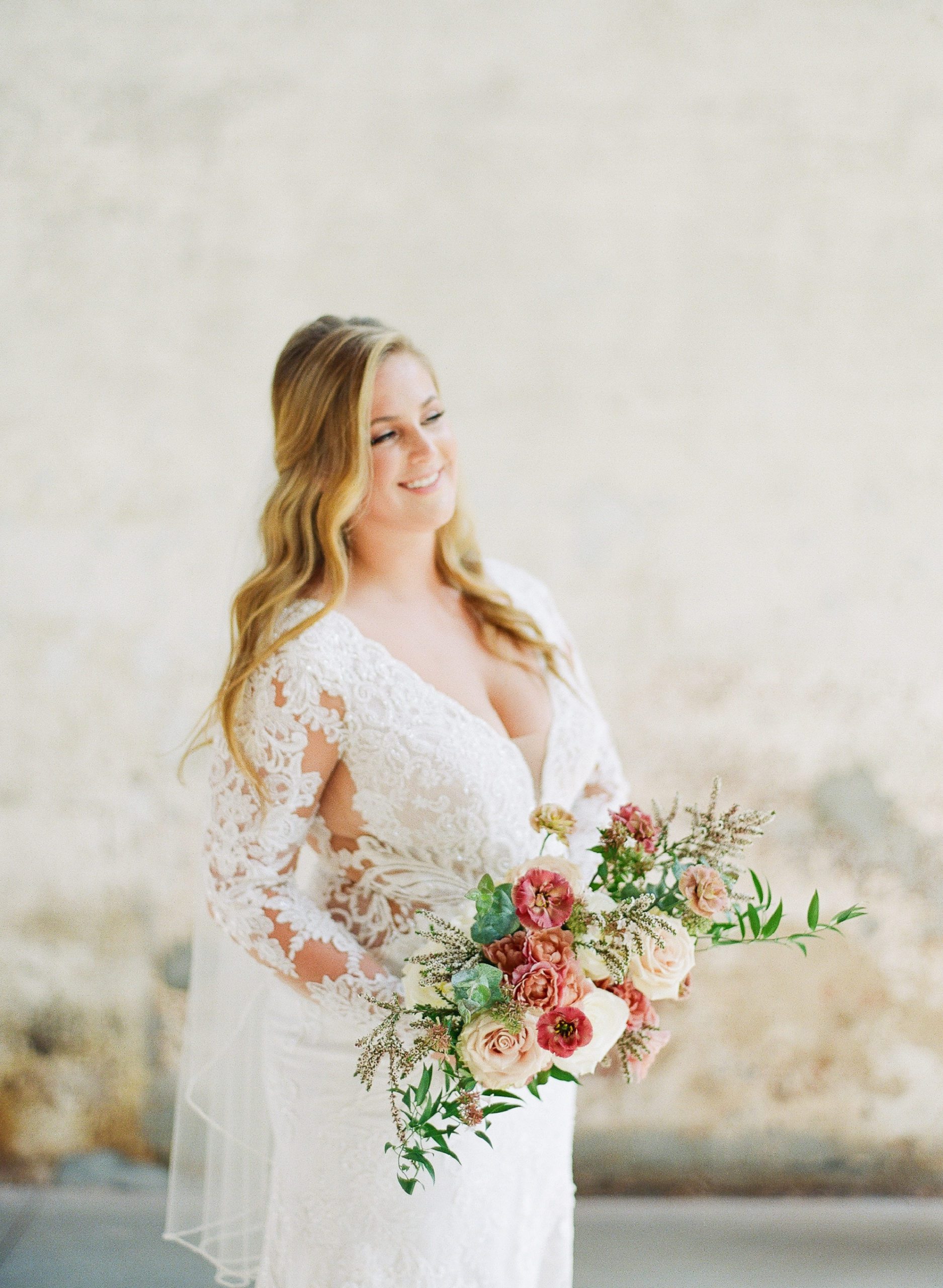 Bride looking off smiling holding bridal bouquet with pink flowers photo