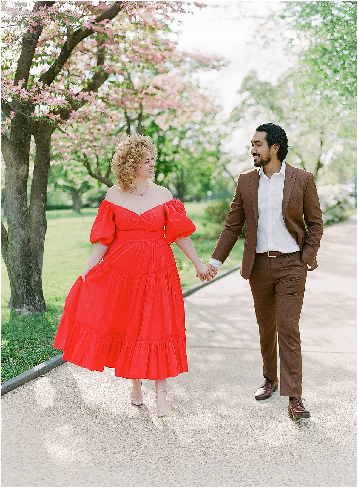 Couple Walking Holding Hands Her Wearing Red Dress He's Wearing Brown Suit Photo