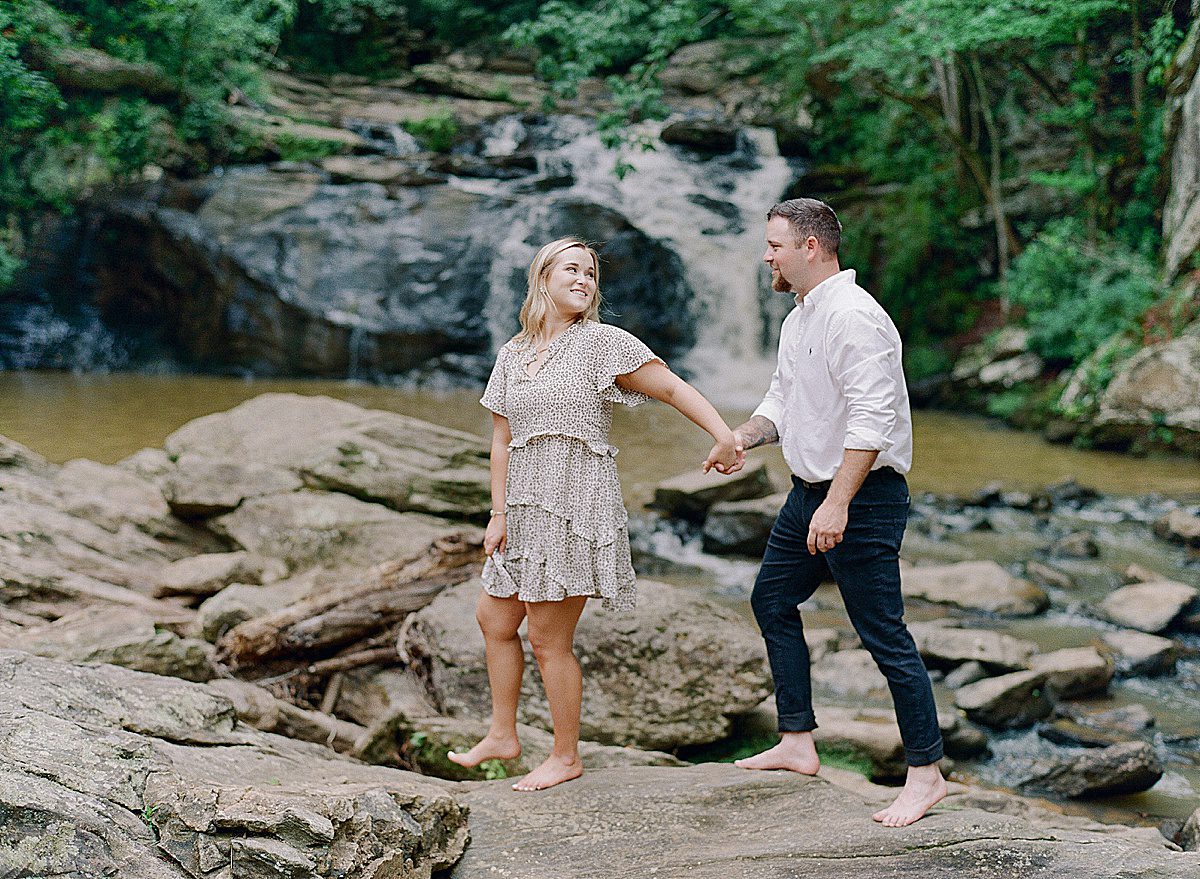 Couple Holding Hands in Front of Waterfall Photo