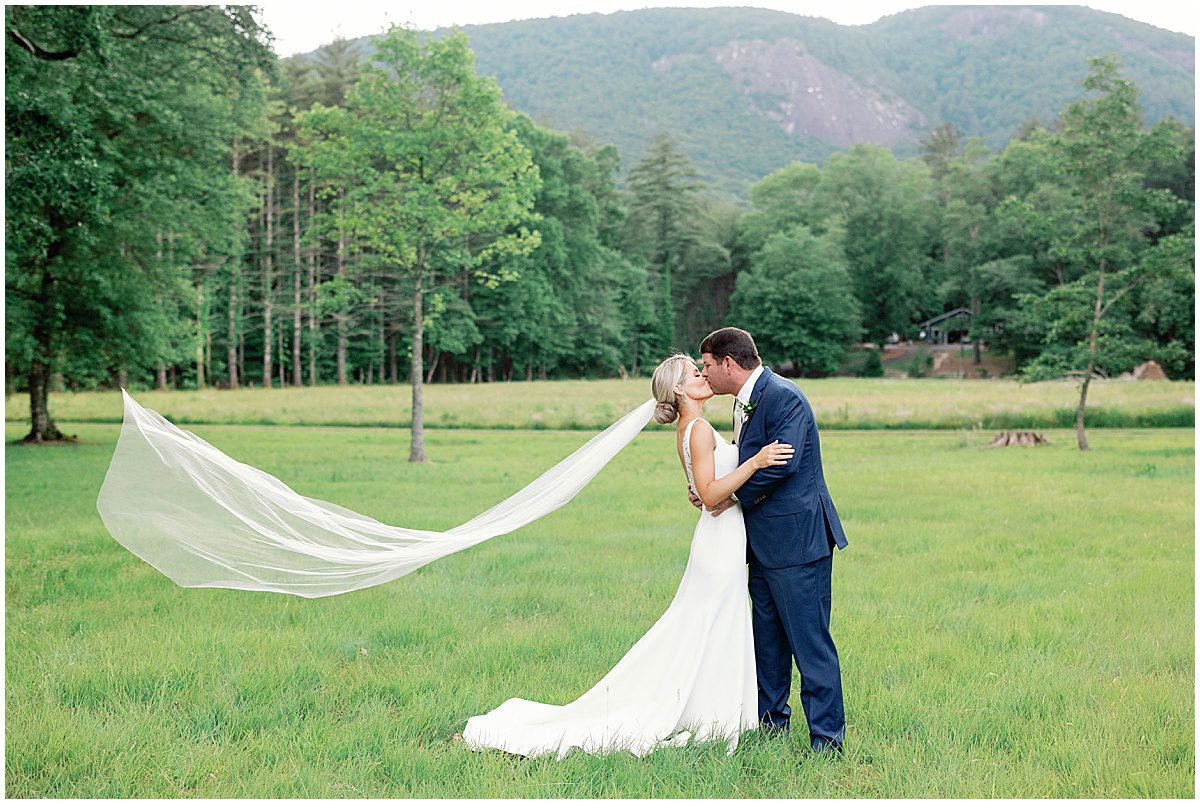 Bride and Groom Kissing with veil Flowing Photo