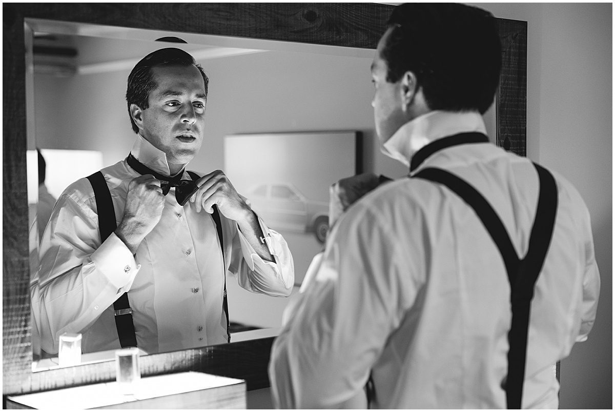 Black and White of Groom Adjusting Tie in Mirror Photo