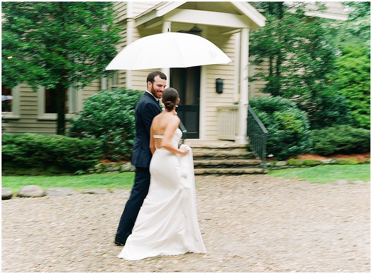 Bride and Groom Walking in The Rain Under an Umbrella Photo