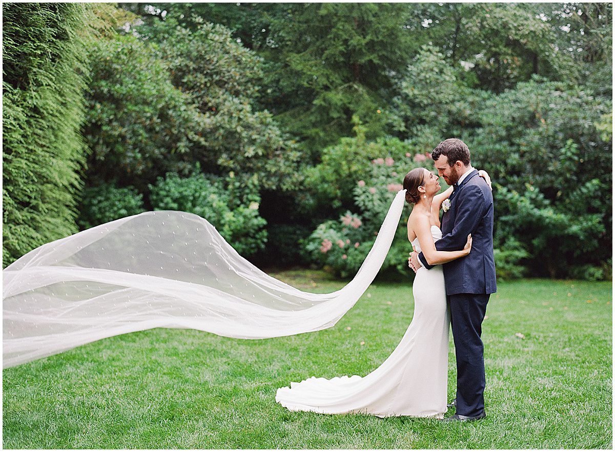 Bride and Groom Smiling at Each Other with Veil Blowing in The Wind Photo