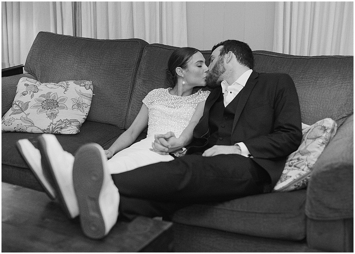 Black and White of Bride and Groom Kissing on Couch after Reception Photo