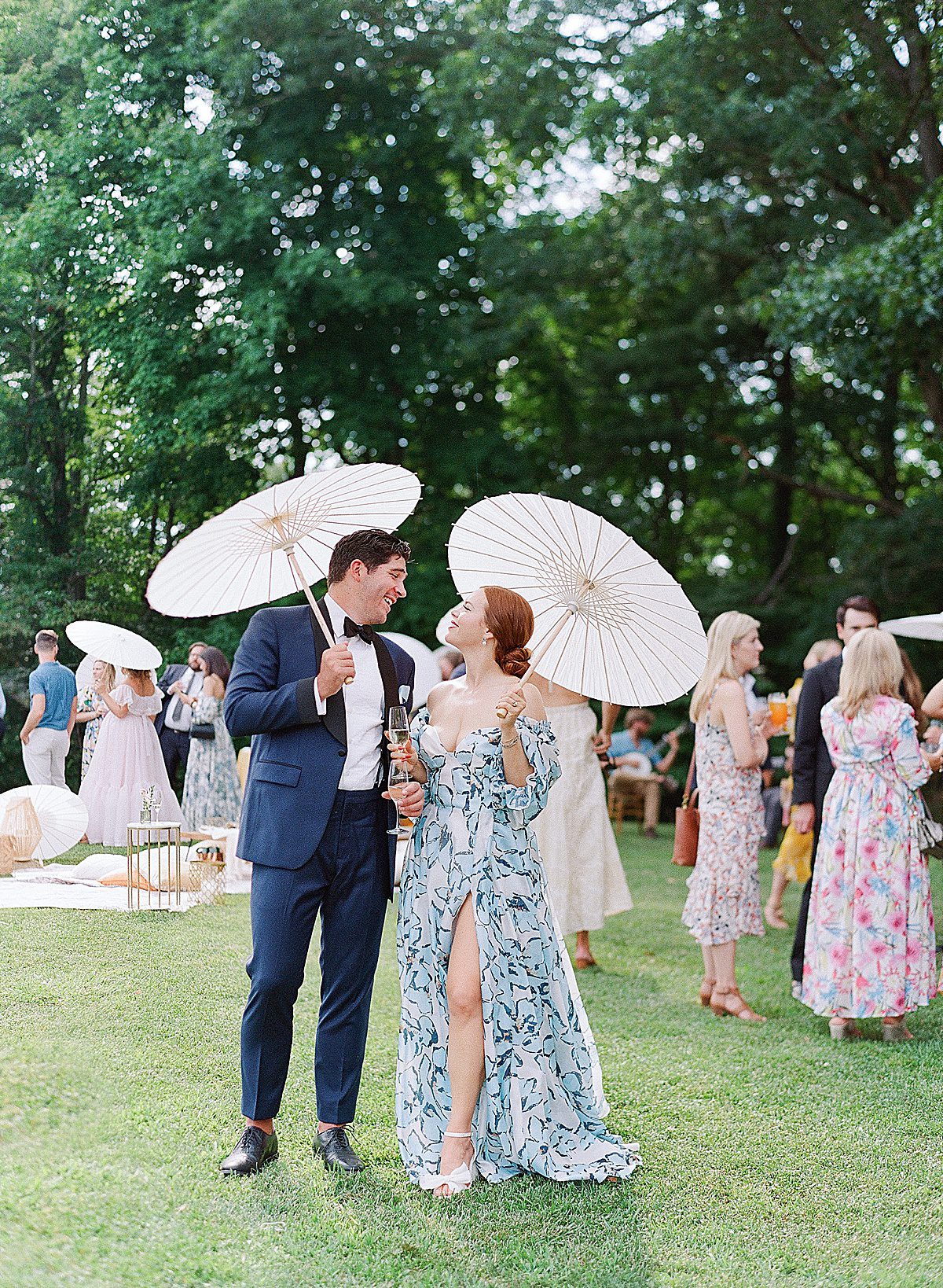 Artistic Asheville Wedding Photographer Captures Bride and Groom Smiling at Each Other Holding Parasols at Cocktail Hour Photo