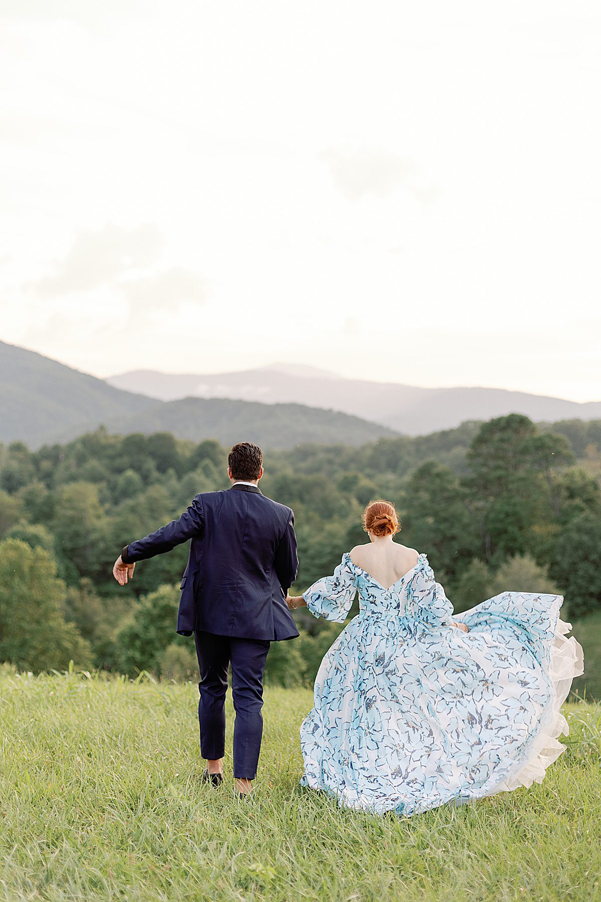 The Ridge Asheville Wedding Venue Bride and Groom Walking through Field Photo