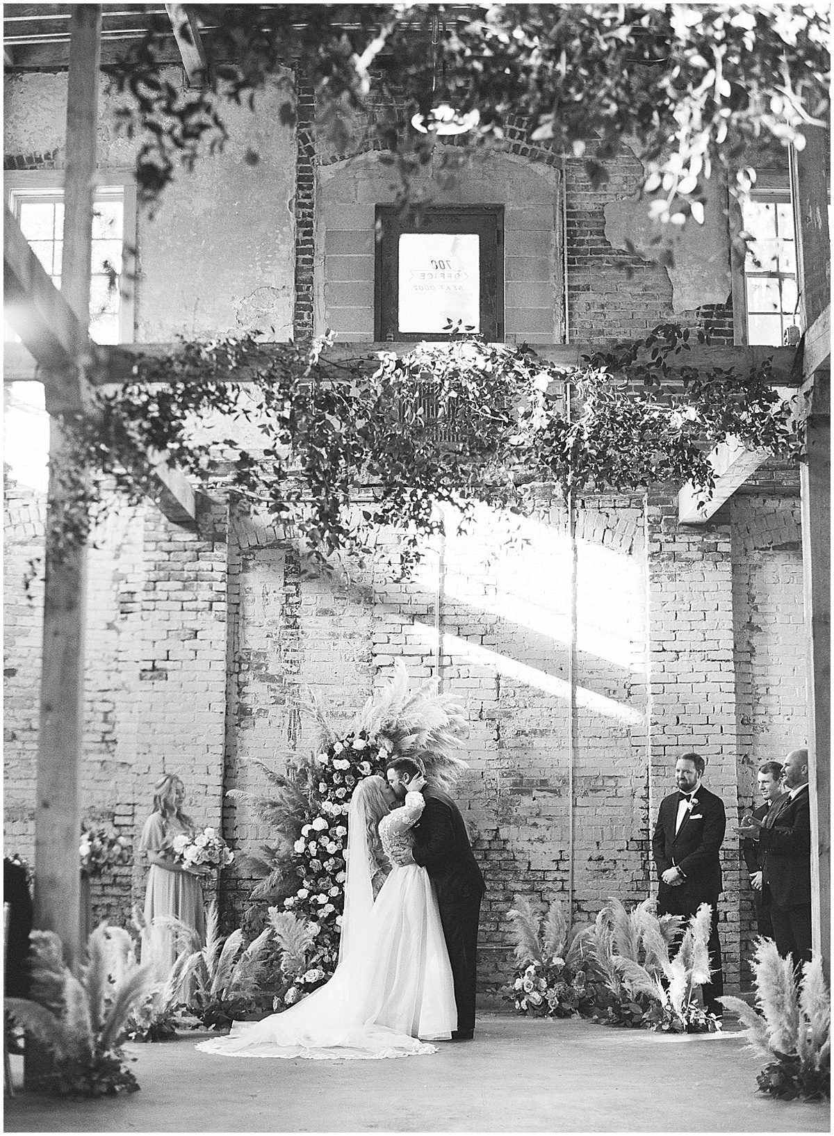Black and White of Bride and Groom Kissing at Alter During Ceremony Photo