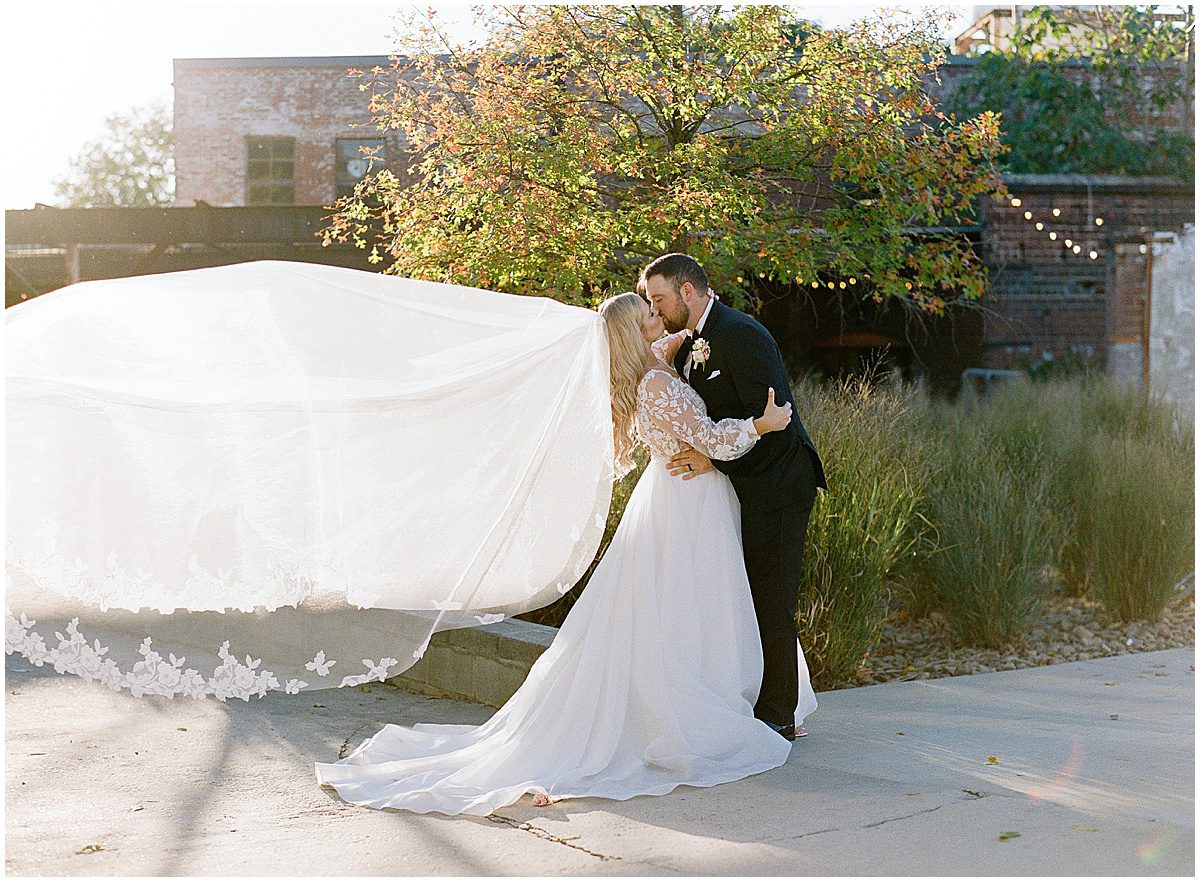 Bride and Groom Kissing with Veil Blowing Photo
