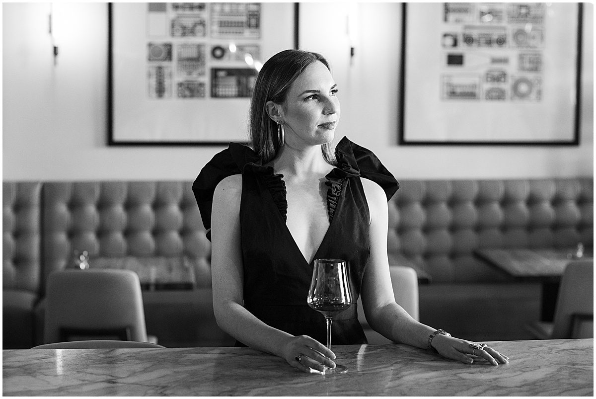 Black and White of a woman in a black dress at a bar with Wine glass Photo