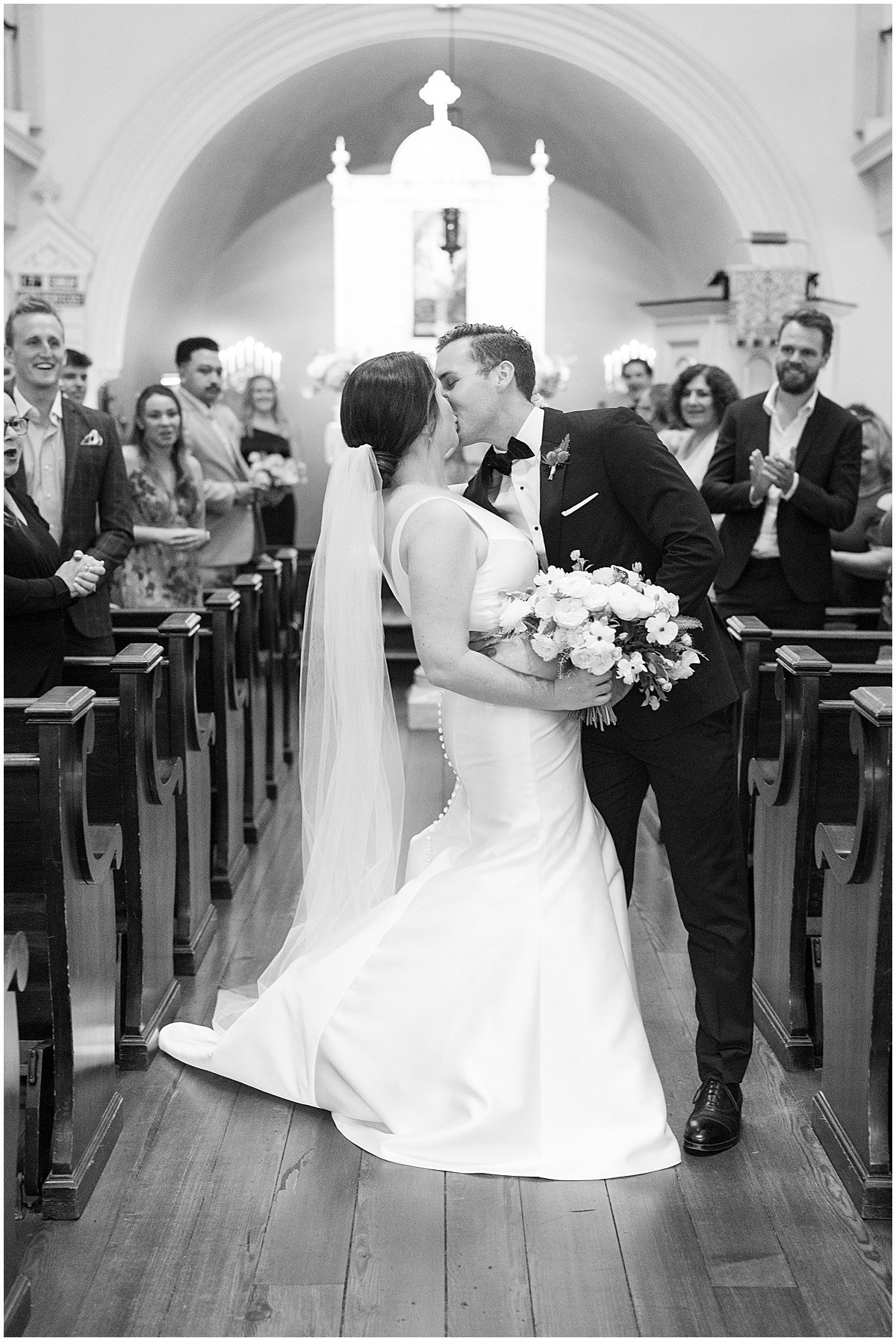 Black and White of Bride and Groom Kissing During Ceremony Recessional Photo