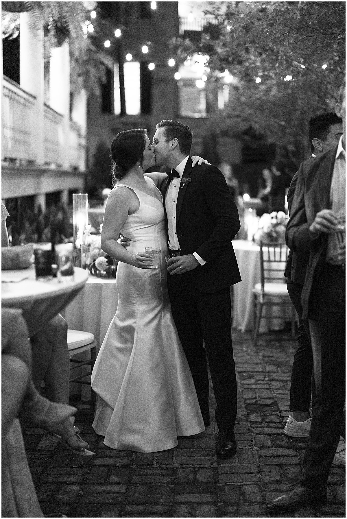 Black and White of Bride and Groom Kissing During Wedding Reception Photo