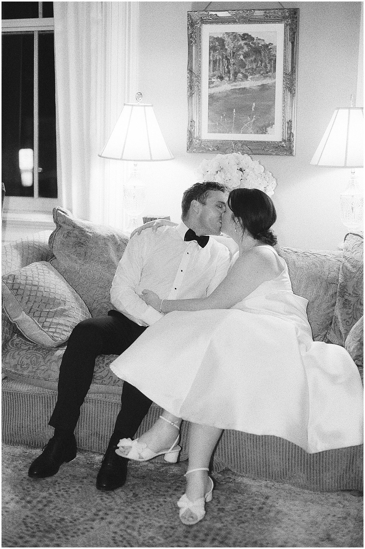 Black and White of Bride and Groom Kissing on Couch Photo