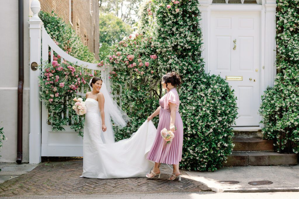 maid of honor holding brides dress walking down street in Charleston 