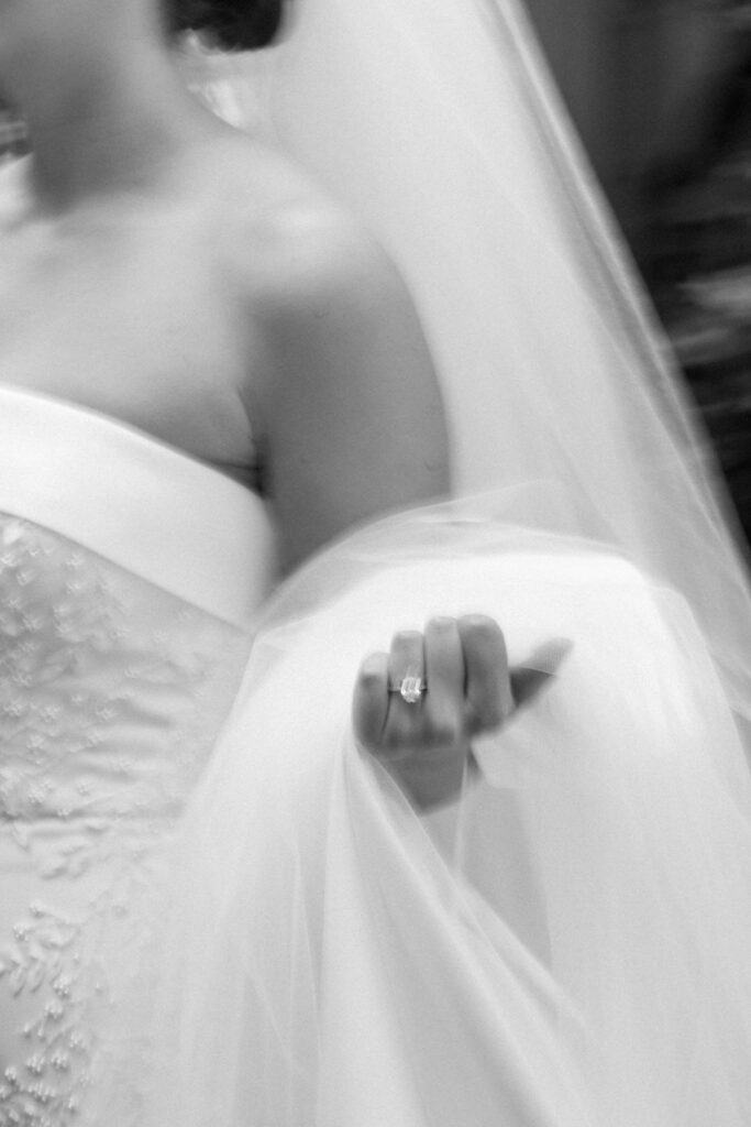 Black and white of brides hand holding veil photo