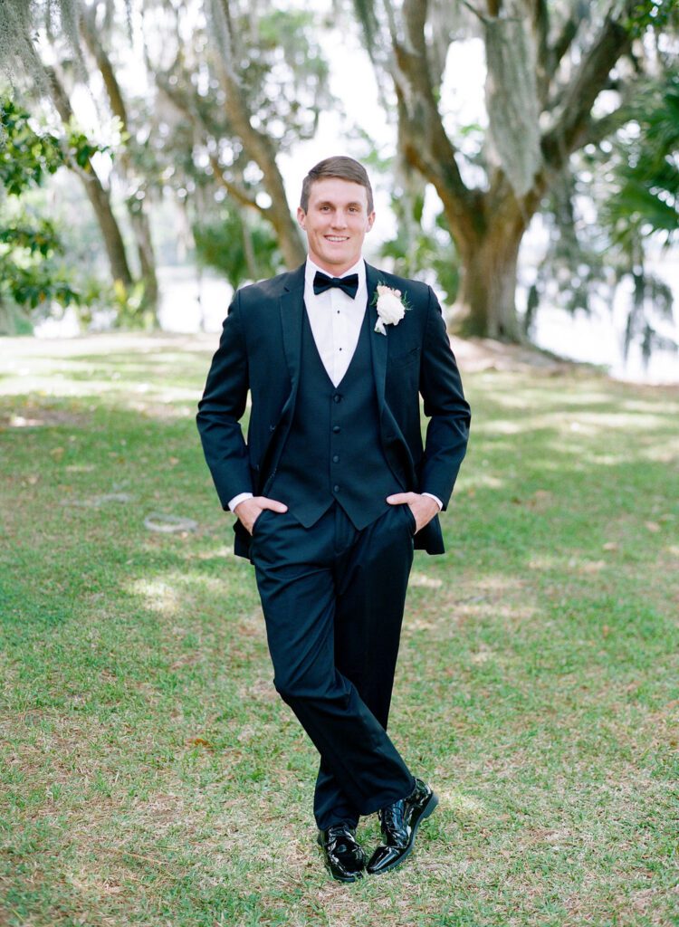 Groom smiling at camera with hands in pockets photo