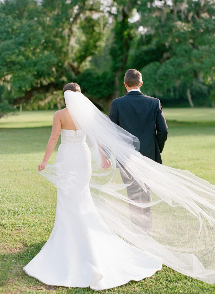 Bride and Groom walking holding hands brides veil blowing