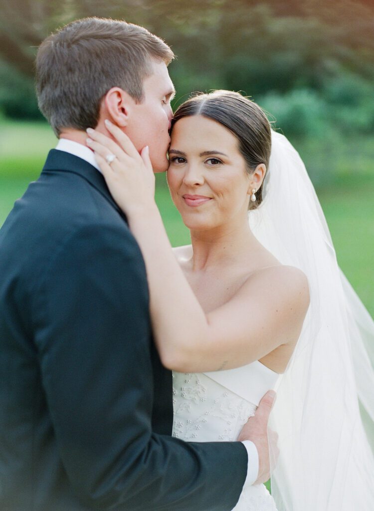 Groom kissing bride on forehead 