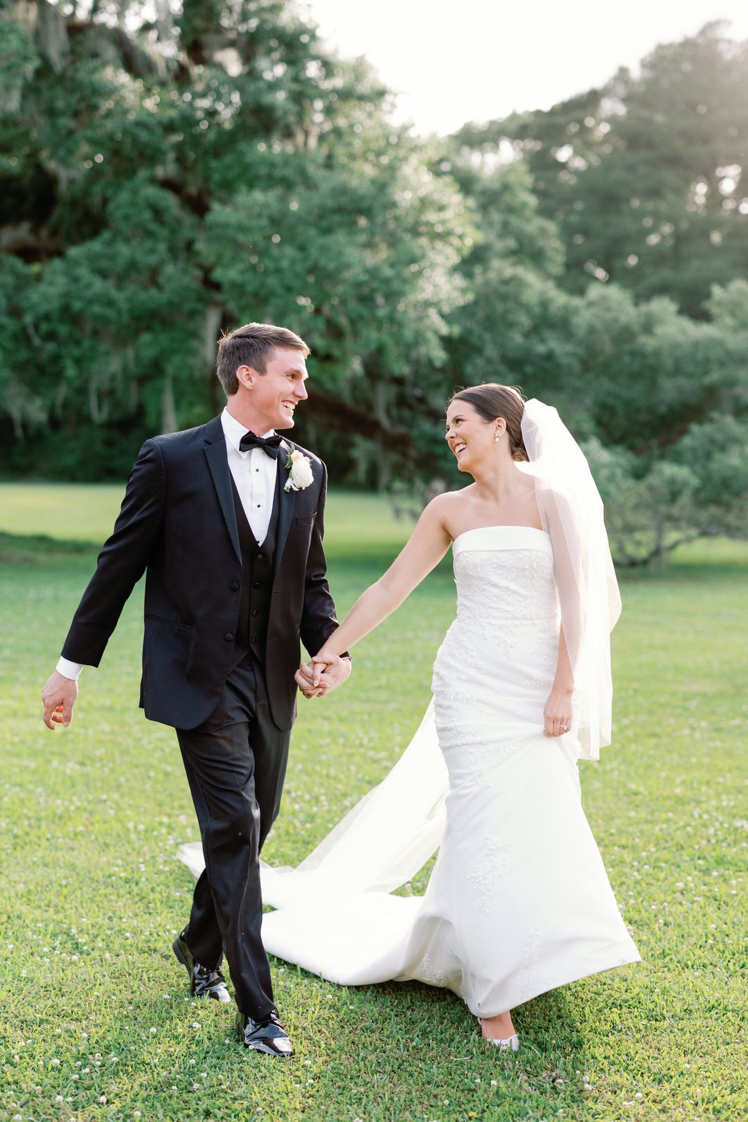 Bride and Groom Holding Hands walking through field at Runnymede in Charleston Photo