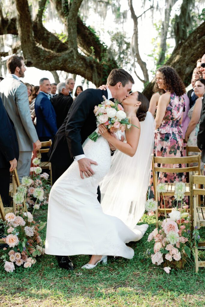 Bride and Groom Kissing at end of aisle — one of their in-the-moment Runnymede Charleston photos