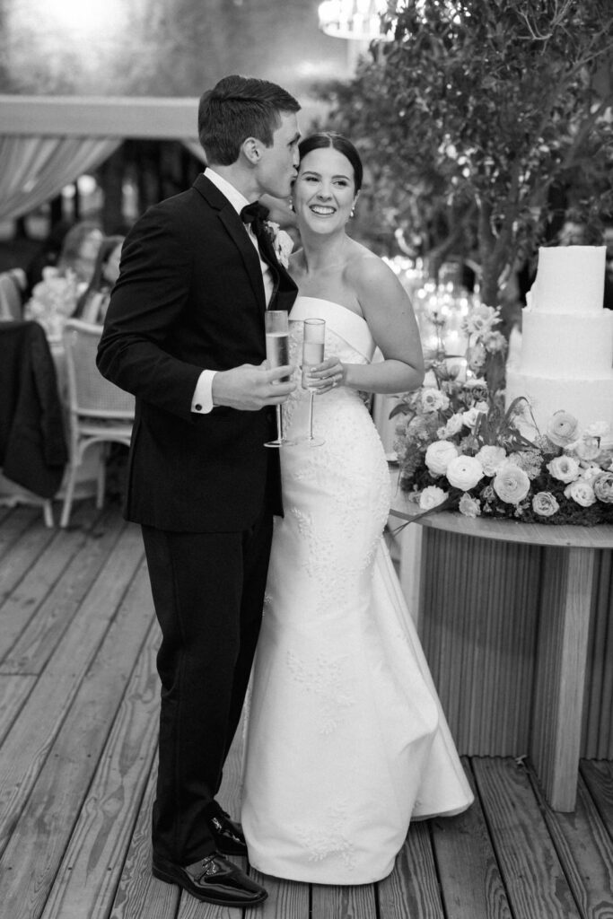 black and white of groom kissing bride 