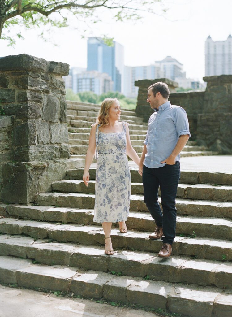 couple holding hands walking down stairs at Piedmont Park Atlanta Engagement