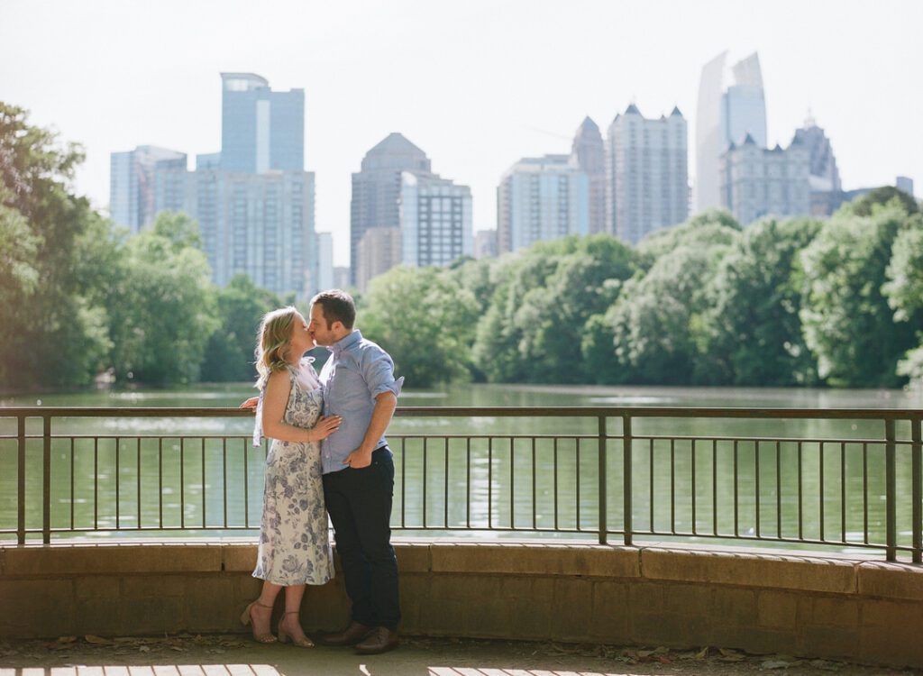 couple kissing in piedmont park with skyline in the background